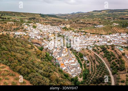 Vue aérienne d'un village espagnol à flanc de colline avec des maisons blanchies à la chaux et des toits en terre cuite, des rues sinueuses parmi les oliveraies et la campagne sauvage, se Banque D'Images
