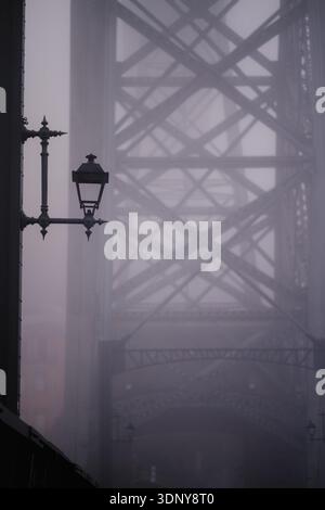 Pont Dom Luis I à Porto enveloppé dans un brouillard dense. La structure en fer s'estompe dans la brume tandis qu'un lampadaire vintage se dresse au premier plan, créant un mini Banque D'Images