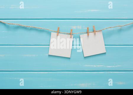 Cartes blanches vierges sur corde, fond en bois bleu Banque D'Images