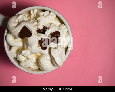 Chocolat chaud avec garniture à la crème fouettée et décorations coeur d'amour Banque D'Images