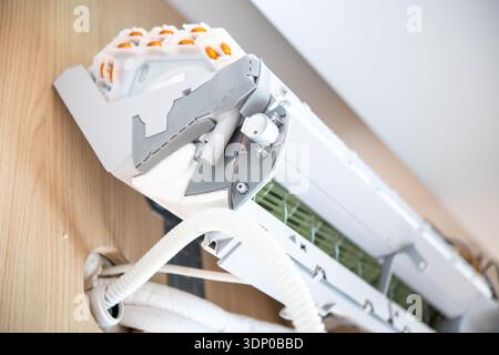 Vue rapprochée d'un climatiseur domestique ouvert montrant les tuyaux internes et les composants montés sur un mur en bois pendant l'installation. Banque D'Images