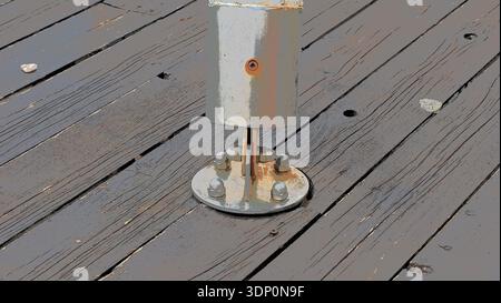 Illustration stylisée montrant une plaque de base en métal rouillé fixée par des boulons à des lames de terrasse en bois usé. Gros plan sur la mise en évidence des détails industriels Banque D'Images