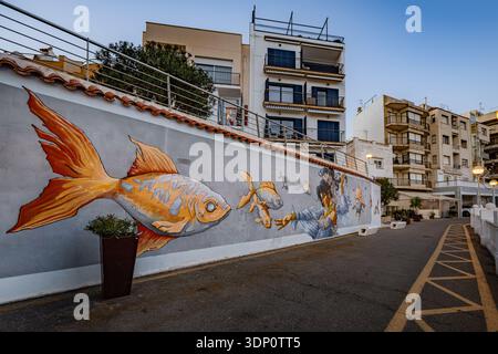 L’Ametlla de Mar, Espagne – murale colorée de rue de grands poissons orange et plongeur peints sur un mur de bord de mer dans la vieille ville Banque D'Images