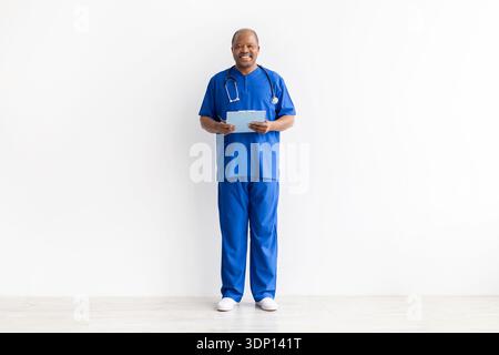 Portrait pleine longueur de docteur masculin noir mature tenant presse-papiers et stylo Banque D'Images