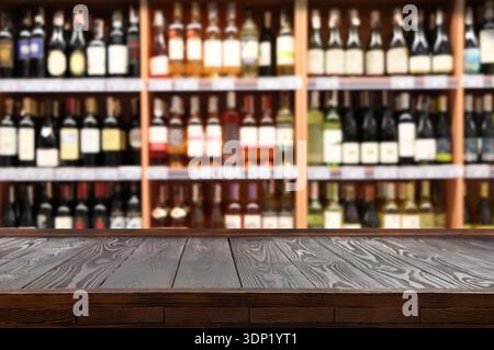 Videz le comptoir de bar en bois contre les étagères floues avec de l'alcool Banque D'Images
