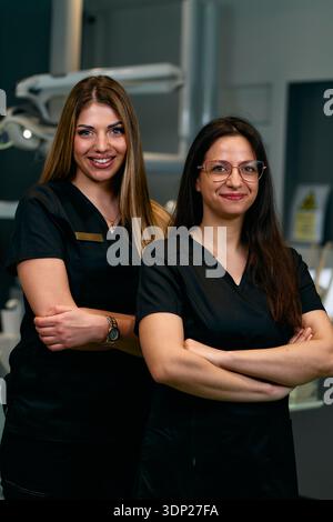 Deux professionnels de la santé confiants dans les gommages se tiennent ensemble dans un cadre hospitalier moderne posant pour la photo Banque D'Images