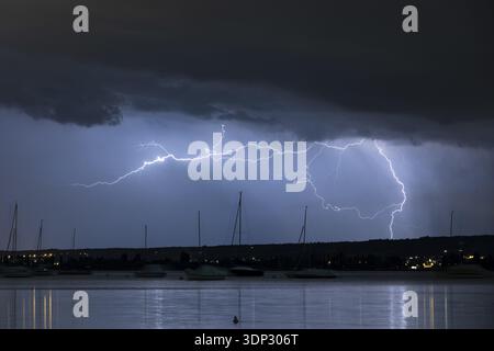 Vue nocturne d'une tempête au-dessus d'un lac, la foudre illumine le ciel avec des bateaux silhouettes, Seegarten, Allensbach, le lac de Constance, Bade-Wuerttemberg, GE Banque D'Images