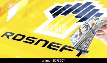 Samara, Russie - 27 mai 2023 : logo Rosneft Oil Company et pile de dollars américains dans la main. Rosneft est l'une des plus grandes compagnies pétrolières russes Banque D'Images