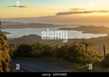 Vue sur la petite ville côtière de Coromandel, Nouvelle-Zélande, depuis les montagnes environnantes. Le soleil se couche sur le Firth of Thames Banque D'Images