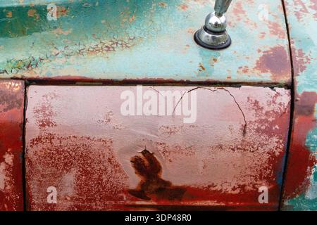 Gros plan d'une porte de voiture vintage avec de la rouille et de la peinture altérée. Banque D'Images