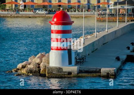Phare rayé rouge et blanc sur une jetée de pierre dans la mer Adriatique au coucher du soleil Banque D'Images