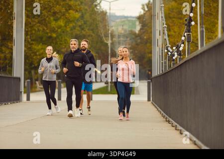 Groupe de coureurs jogging ensemble sur le pont de la ville dans le parc pendant l'entraînement de fitness Banque D'Images
