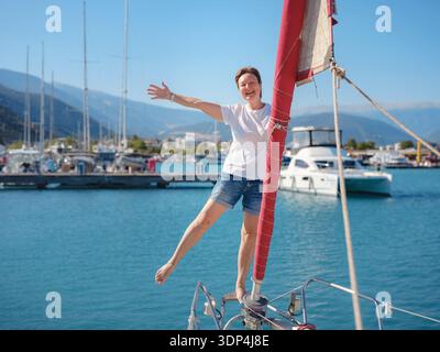 Femme marin tient le tissu de voile blanc se préparant à lever des voiles sur le yacht. L'activité physique et les compétences de maniement de bateau sont montrées pendant la préparation pour le voyage en voilier près de la côte de Finike. Banque D'Images