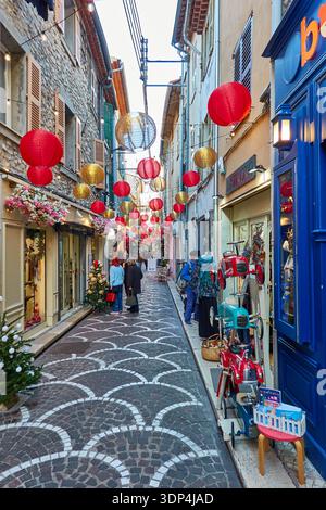 Rue commerçante festive de Noël avec lanternes suspendues et décorations de vacances dans Narrow Alley Banque D'Images
