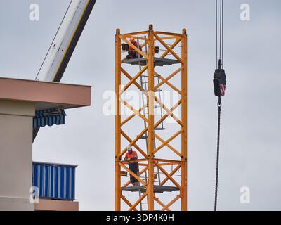 Ouvriers de la construction sur la tour de grue inspectant la structure avec équipement de sécurité et travail d'équipe en hauteur Banque D'Images