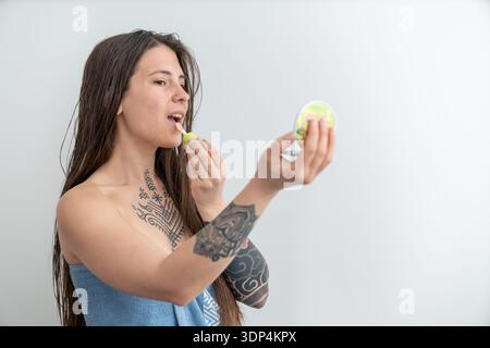 Femme appliquant le brillant à lèvres regardant dans le miroir de poche Banque D'Images