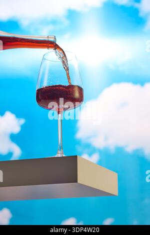 Verre de vin rouge versé contre le ciel Banque D'Images