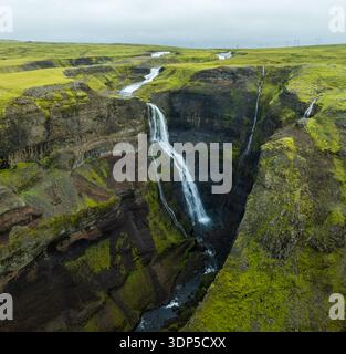Vue aérienne des cascades qui plongent dans les falaises accidentées, contrastant avec la mousse verte luxuriante, Haifoss, Islande. Banque D'Images