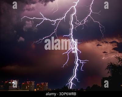 Orage. Éclair épais sur le fond du ciel nocturne. Tempête électrique dans la ville de nuit. Les éclairs éclairs éclairent les nuages orageux. La tempête électrique éclate au-dessus du paysage urbain Banque D'Images