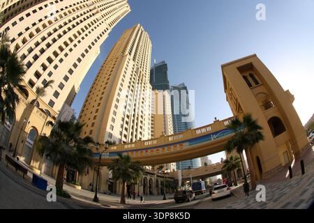 Perspective en angle bas à l'objectif fisheye des immeubles d'appartements de luxe imposants et des palmiers dans le quartier de Dubai Marina sous un ciel bleu. Banque D'Images