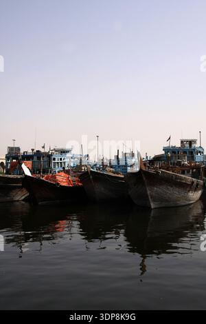 Bateaux de charge traditionnels en bois Dhow regroupés et amarrés au Dubai Creek avec des reflets d'eau calmeBateaux de charge traditionnels en bois Dhow regroupés Banque D'Images