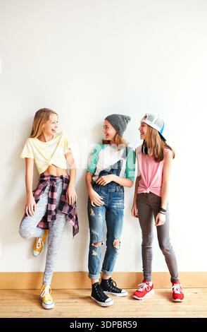 Mode, conversation et groupe d'adolescents par le mur pour se lier, l'amitié ou rire ensemble. Heureux, l'espace et les filles traînent avec cool Banque D'Images