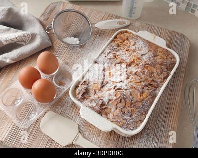 Gâteau éponge avec pétales, flocons d'amande et sucre en poudre. Dessert et fête à la maison. Cuisine et passe-temps. Banque D'Images