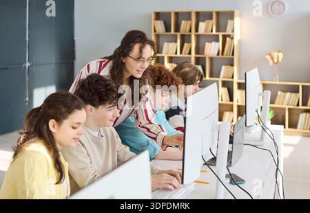 Les élèves du secondaire programment avec les conseils des enseignants dans le laboratoire informatique lumineux Banque D'Images