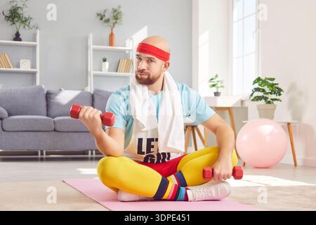 Portrait d'homme sérieux exerçant avec des haltères à la maison Banque D'Images