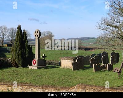 Vue du cimetière et du monument aux morts dans le parc de l'église All Saints, Lamport, avec la campagne du Northamptonshire en arrière-plan. Banque D'Images
