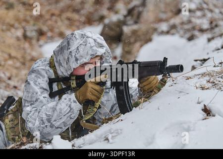 Soldat dans un fusil de visée de camouflage d'hiver blanc de Snowy Foxhole pendant l'entraînement par temps froid Banque D'Images