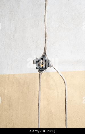boîte de jonction électrique ouverte avec conduit métallique monté sur un mur en béton. Détail industriel minimal montrant le câblage exposé et l'infrastructure backgr Banque D'Images