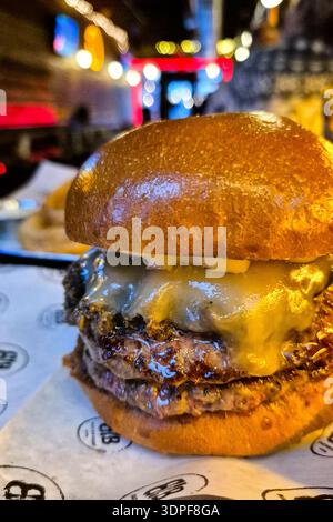 Une vue rapprochée fantastique d'un hamburger de bœuf juteux avec deux galettes et du fromage cheddar fondu, servi dans un dîner à New York City, NY, États-Unis Banque D'Images