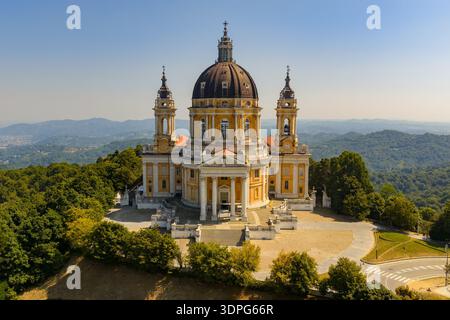 Vue aérienne de la basilique baroque de Superga au-dessus de Turin, montrant son dôme central, ses clochers jumeaux et sa terrasse perchée au milieu des pentes boisées. Banque D'Images