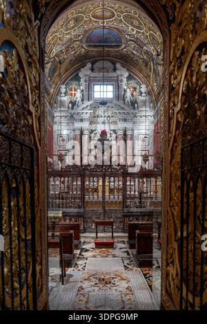Valletta, Malte - 13 août 2025 : vue à travers des portes sculptées dorées dans la Co-cathédrale John, la Valette : nef baroque avec plancher de tombeau en marbre, forgé-ir Banque D'Images