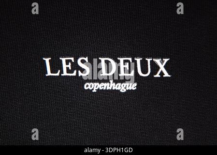 Logo de la marque de mode les deux Copenhague sur les vêtements noirs. Texte brodé blanc sur texture de tissu côtelé foncé. Banque D'Images