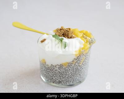 Pudding aux graines de chia recouvert de mangue, de yogourt et de granola, recouvert de menthe fraîche Banque D'Images