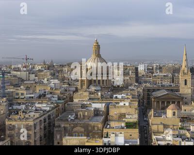 Vue aérienne du dôme doré et de la flèche perçant la ligne d'horizon au-dessus des bâtiments historiques et des rues étroites de la Valette, Malte., la Valette, la Valette, Banque D'Images