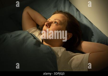 Pensant femme sans sommeil sur le lit dans la chambre à coucher la nuit. l'insomnie à domicile. gros plan Banque D'Images