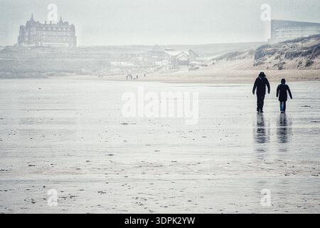 Newquay, Cornouailles, Royaume-Uni. 15 février 2026. Météo Royaume-Uni : fortes pluies à Fistral Beach, Newquay. Photo : couple blotti marchant sur une plage saturée vide. Crédit : Nidpor/Alamy Live News Banque D'Images