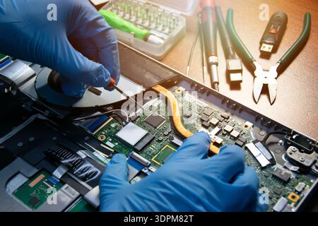 Vue latérale d'un technicien réparant un ordinateur portable. Banque D'Images