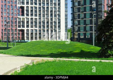 Immeubles d'appartements contemporains avec façades élégantes et une colline verte bien entretenue dans un parc public dans un quartier résidentiel Banque D'Images