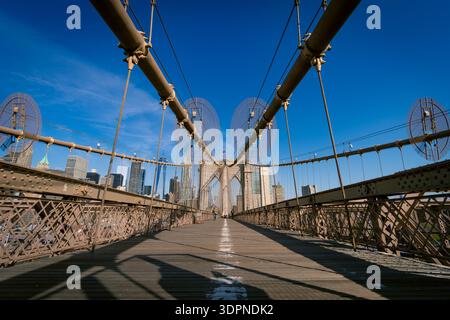 Vue symétrique en angle bas de la passerelle piétonne du pont de Brooklyn avec la ligne d'horizon de Manhattan en arrière-plan. Emblématique monument de New York Banque D'Images