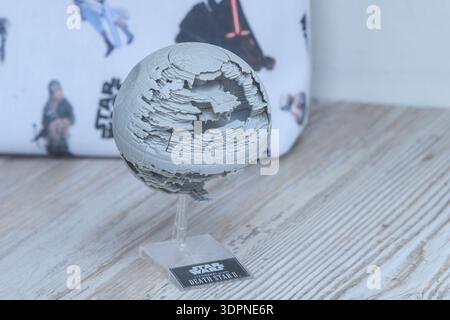 Lieu inconnu - 12 mai 2021 : un modèle détaillé de Star Wars Death Star II est exposé sur une surface en bois, avec un tissu sur le thème Star Wars avec des illustrations de personnages en arrière-plan. Banque D'Images