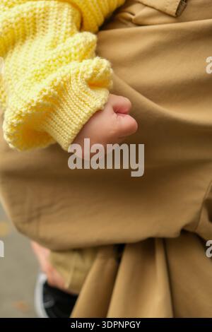 Gros plan de la main de l'enfant en pull jaune Banque D'Images