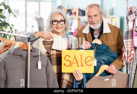 Couple âgé debout dans le magasin avec affiche Banque D'Images