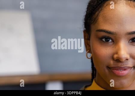 Femme afro-américaine posant en studio près de la toile portant un col roulé moutarde montrant des cheveux tressés Banque D'Images