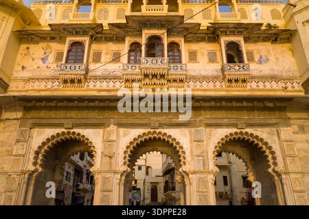 Udaipur, Inde - 22 mars 2022 : vue détaillée des arches en pierre historiques et de la façade supérieure décorée à l'entrée du Gangour Ghat, avec des arches sculptées, des balcons et des œuvres murales peintes visibles à la lumière du soleil. Banque D'Images