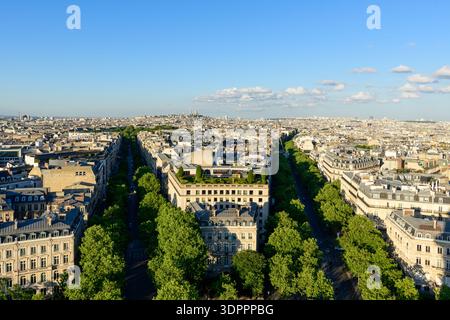 Paris, France - 11 mai 2022 : vue surélevée de Paris montrant des boulevards bordés d'arbres, des bâtiments résidentiels et commerciaux, et la ligne d'horizon de la ville sous la lumière du jour claire avec la basilique du Sacré-cur visible au loin. Banque D'Images