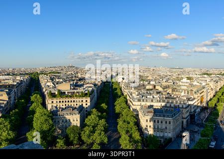 Paris, France - 11 mai 2022 : vue surélevée de Paris montrant des boulevards bordés d'arbres, des bâtiments résidentiels et commerciaux, et la ligne d'horizon de la ville sous la lumière du jour claire avec des nuages dispersés. Banque D'Images